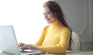 Woman working from laptop computer on dining room table.