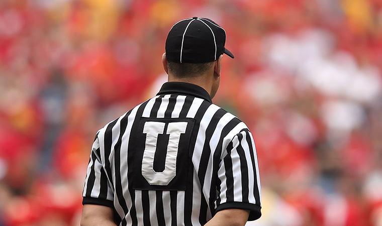 Football referee standing in front of crowd.