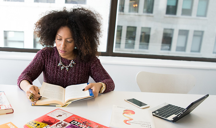 Woman reading book at a desk.