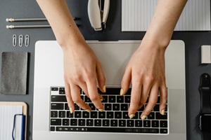 person typing on a laptop and sharing contact center trends for 2025