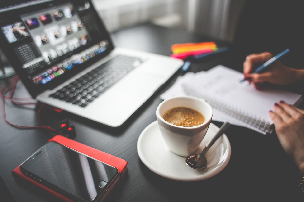 person working at desk, taking notes during a meeting with coffee on their desk